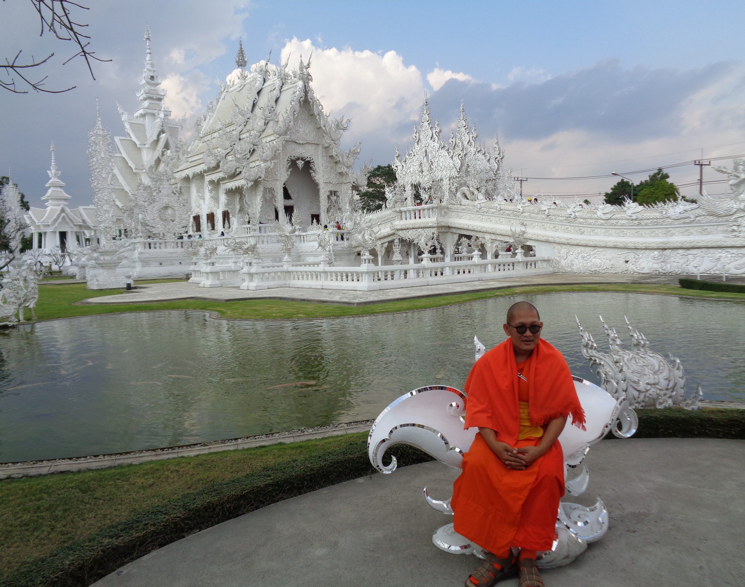 Ein Mönch posiert vor dem weißen Tempel in Thailand.