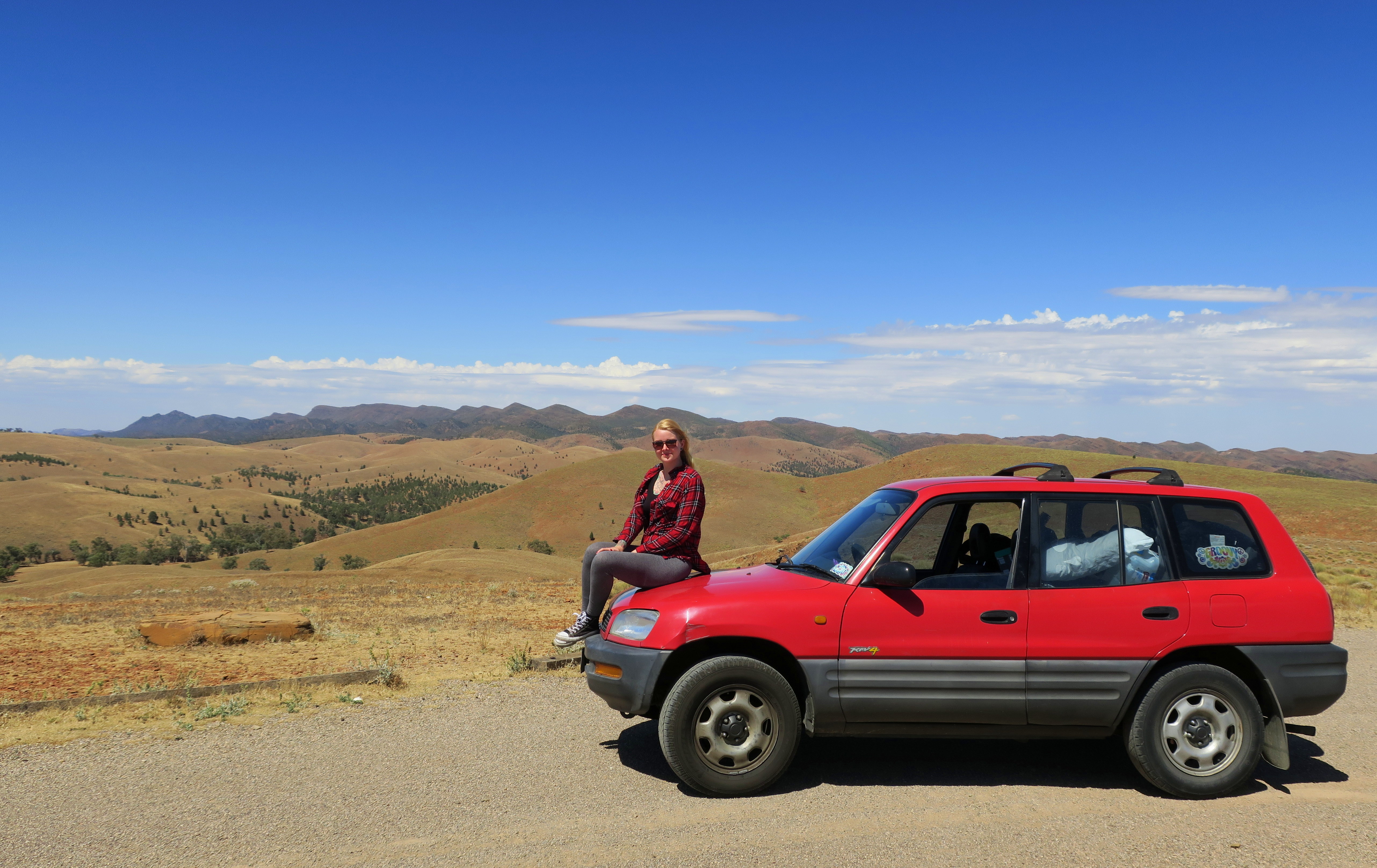Jacqui sitzt auf ihrem Auto im Outback von South Australia, 2016.