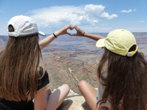 Zwei Mädchen formen ein Herz vor einem Canyon. Quelle: Pixabay